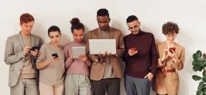 Group of diverse people using different devices like laptops and smartphones.